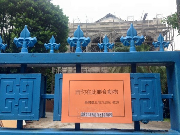 台北地方法院的大門貼出一張橘底黑字的公告，上面斗大的字寫著「請勿在此餵食動物」，最後署名寫上「台灣台北地方法院敬啟」。（圖擷取自爆料公社）