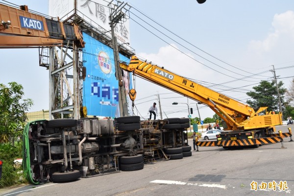 載運綠豆的大貨車，疑因重心失衡翻覆，當場壓死2名在路口張貼廣告的工人。（記者蘇福男攝）