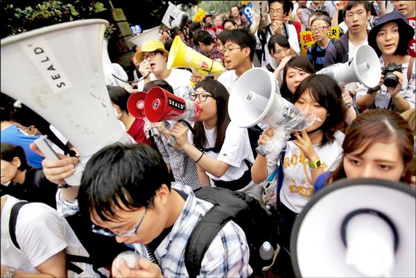 日本學運組織「學生捍衛自由民主緊急行動（SEALDs）」十八日在國會外拿著大聲公呼口號，反對安倍政府力推的新安保法將在國會中過關。（路透）