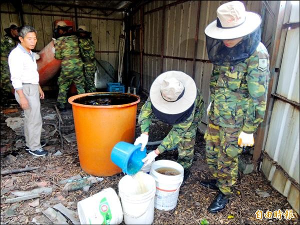 塑膠桶內儲滿廢水孳生孑孓，軍方分批舀出水進行清除。（記者林孟婷攝）