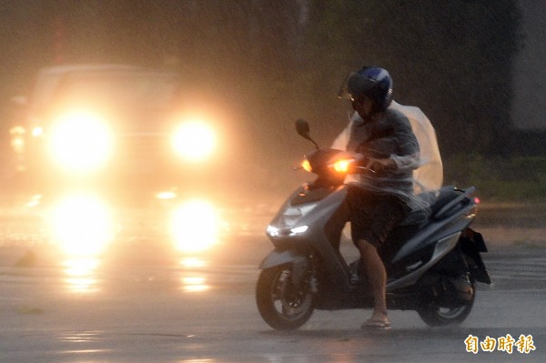 強颱杜鵑挾帶風雨而來，台北市街頭一片霧茫快看不清路，一陣一陣的強風襲來，迫使騎士不得不在路口放下雙腳慢慢前行。（記者叢昌瑾攝）