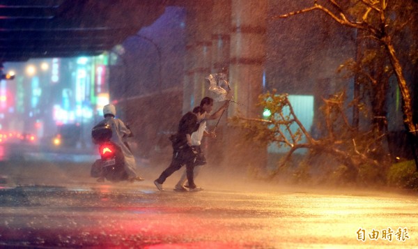 杜鵑颱風來襲，今天（28日）入夜後台北市風雨加劇，冒險外出的民眾，傘被吹到開花，險象環生。（記者張嘉明攝）