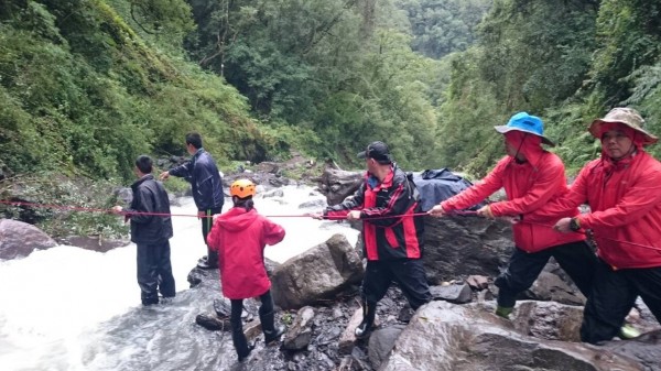 新竹縣尖石鄉鎮西堡山區有17名登山客受困，搜救隊員今早入山，架繩協助他們渡溪脫困。（圖由新竹縣政府消防局提供）