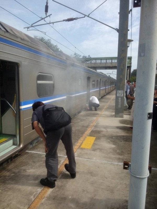 台鐵區間車煞車過熱冒煙，旅客趕緊幫忙查看列車底盤冒煙處。（翻攝自《爆料公社》）