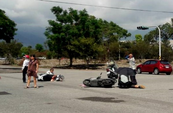 潘翁疑因中風衝撞橫向機車倒地，1名路經軍人目擊，好心撐傘為老人家遮擋豔陽。（記者陳賢義翻攝）