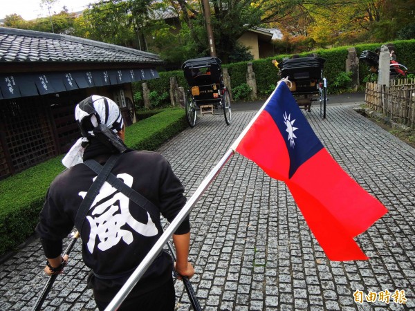 導遊謝銘煌贈送國旗，隨著日本人力車飄揚在京都嵐山巷道。（記者黃旭磊攝）