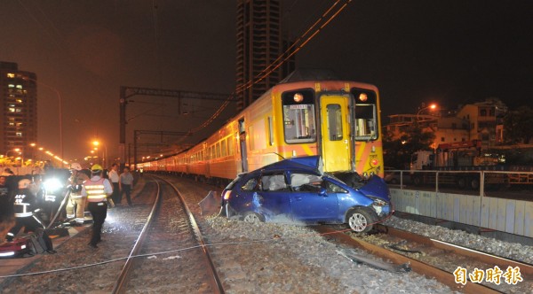 小客車撞上火車後，被卡在火車底下，目前車上女駕駛受困車中、重傷昏迷，現場仍在搶救中。（記者黃志源攝）