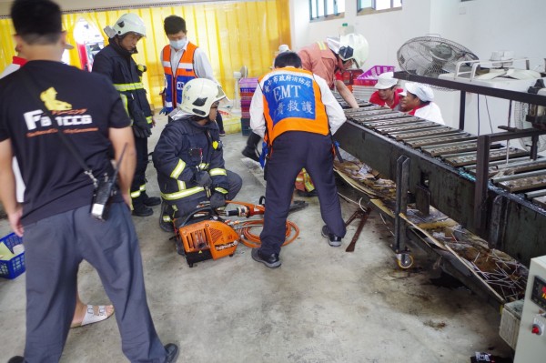 糖果工廠女工手遭機器夾住，警消使用器材準備破壞機器。（記者李忠憲翻攝）