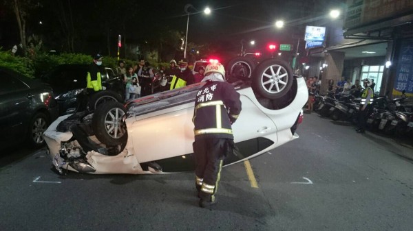 小轎車疑閃車不慎翻覆，警消趕抵現場救援。（記者曾健銘翻攝）