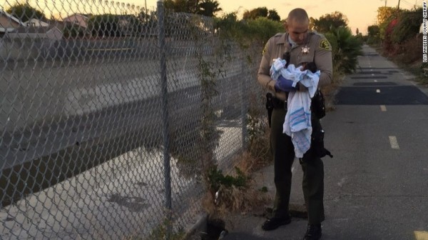 洛杉磯警局兩位警務人員在一個步道旁的坑洞裡，發現了被柏油碎片所覆蓋的女嬰，警長辦公室指出，這位嬰兒當時摸起來很冷，被包裹在似乎是醫院的毯子裡。（圖擷自《CNN》）