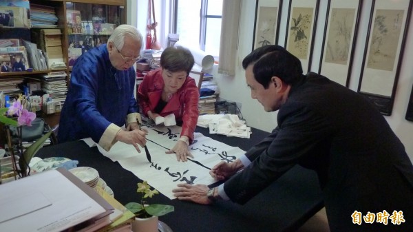 歐豪年現場揮毫寫「開張天岸馬、奇逸人中龍」，馬幫忙拉宣紙。（記者游蓓茹攝）