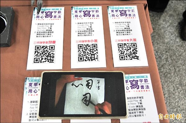 久未提筆寫不出來？趕快拿手機掃QR Code條碼，立刻上網看「三分鐘學會書法」影片，看老師運筆寫「用心」二字，讓年輕人重拾對寫字的興趣。（記者花孟璟攝）