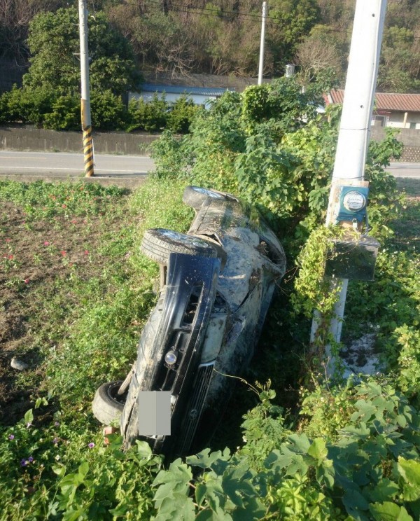 失控「犁田」的小客車，側翻在農田中，乍看像「依偎」著電線桿。（記者張勳騰翻攝）