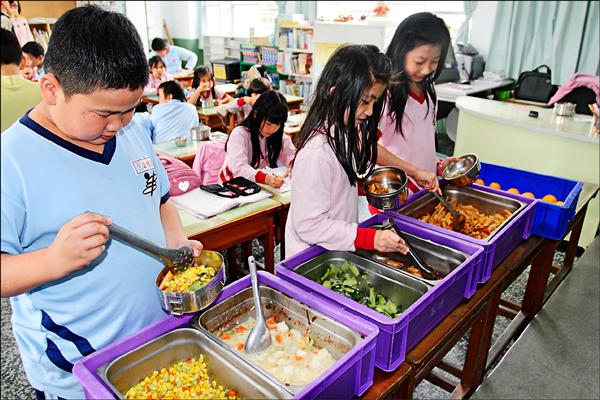 立法院院會昨三讀通過各級學校全面禁用基改食品，教育部試算，明年起學生營養午餐每餐成本恐將增約五元。圖為學童使用營養午餐情形。（資料照）