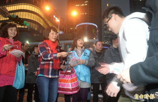 國民黨副總統候選人王如玄，晚間到台北捷運市府站附近路口發送暖暖包，也順便祝民眾新年快樂。（記者林正堃攝）