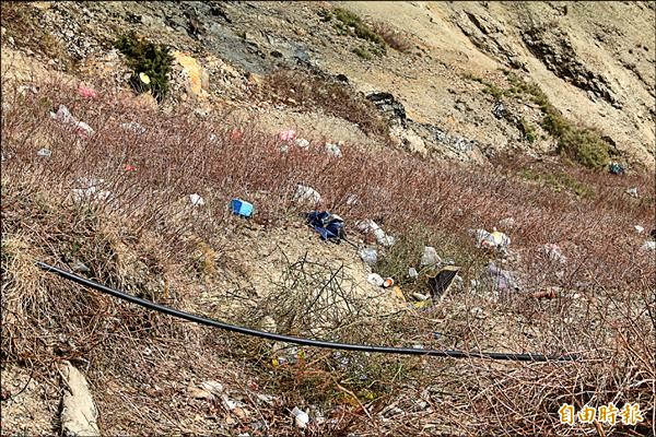 合歡山武嶺一帶遊客隨手丟棄的垃圾，被強風吹下山坡，變得難以清除。（記者佟振國攝）