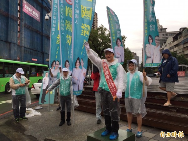 劉國隆穿雨衣冒雨站口拜票。（記者蔡淑媛攝）