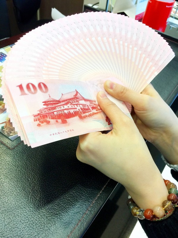 A woman at a bank in Taipei yesterday fans out a stack of NT100 bills.
Photo: Lee Ching-hui, Taipei Times