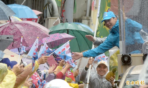 國民黨總統候選人朱立倫冒雨展開車隊掃街行程。（記者王敏為攝）