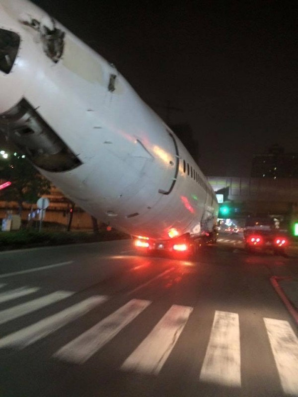 飛機機身在馬路上被拖板車載著趴趴著，讓路人看傻了眼，但託運業者表示，這只是「中小型物件」。（圖取自爆料公社）