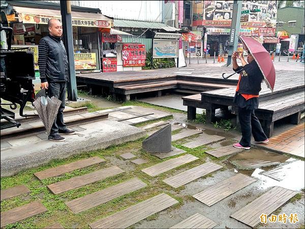 集集火車站廣場火車頭展示區，石板草地鋪面年久失修下雨易積水，遊客拍照還得避開。（記者劉濱銓攝）