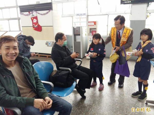 佛光山幼童軍在新營火車站發送臘八粥，旅客歡喜、吃得暖呼呼。（記者王涵平攝）