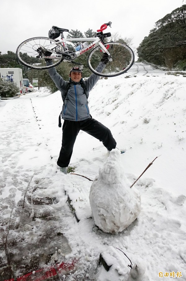 大屯山二子坪24日凌晨開始降下大雪，到白天已成雪白一片，一位黎姓民眾花了二.三小時，從泰山騎腳踏車上山賞雪。（記者方賓照攝）