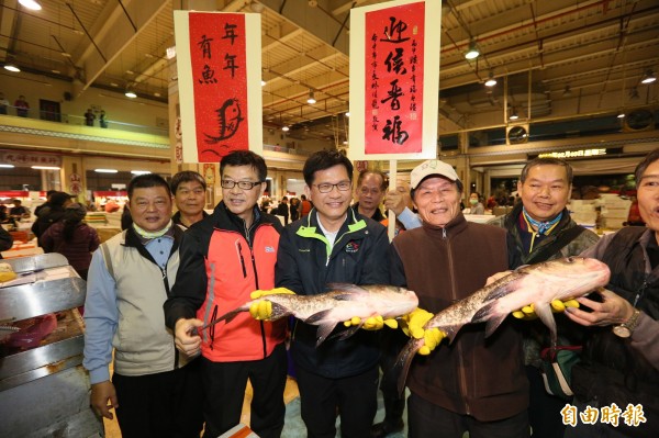 市長林佳龍（左三）巡視魚市場，攤商快樂捧著魚跟市長合照（記者蘇金鳳攝）