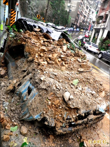 停放在路邊的小客車被土石壓毀。（記者盧賢秀攝）