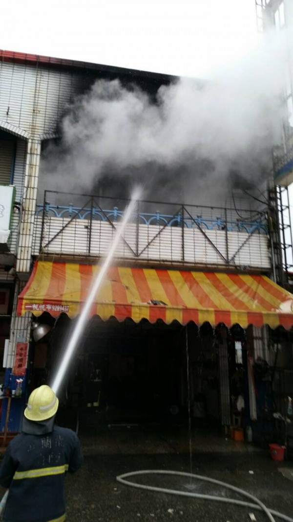 宜蘭市泰山路一家洗車場火警，2樓冒出濃煙，消防人員射水搶救。（記者江志雄翻攝）