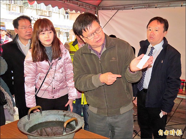 新北市野柳神明淨港文化祭活動昨天開幕，圖為副市長陳伸賢「水中顯符」的體驗，陳伸賢仔細端詳籤詩浮出的文字。（記者俞肇福攝）