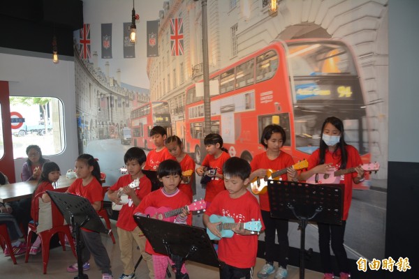 倫敦餐館以英國地鐵站為主題，孩子們在地鐵站布幕前拉起烏克麗麗，就像是在英國街頭表演，有著異國風情。（記者游明金攝）