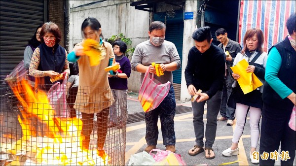 倖存的林文祥（中）與居民一同燒紙錢去煞氣求平安。（記者陳薏云攝）