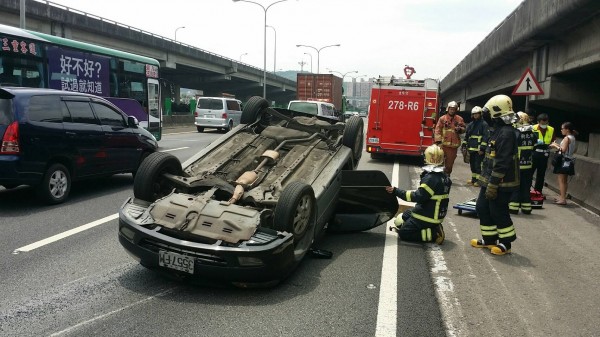 轎車在國道上翻覆，警消人員趕赴現場救援，所幸高姓女駕駛已自行脫困。（記者曾健銘翻攝）