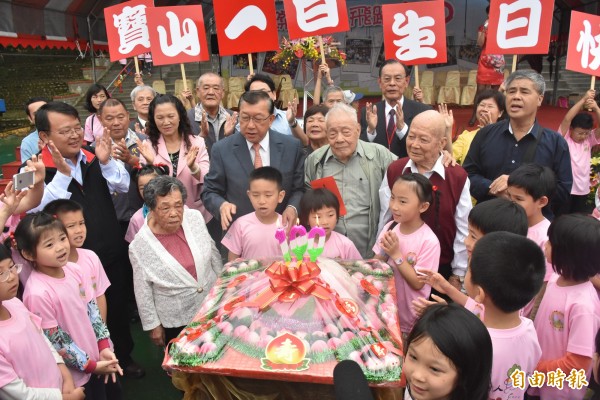 新竹縣寶山國小一百歲生日，百歲校友何寅生、黎添霖、魏森妹和縣長邱鏡淳一起代表切壽桃造型的特製蛋糕慶祝。（記者廖雪茹攝）