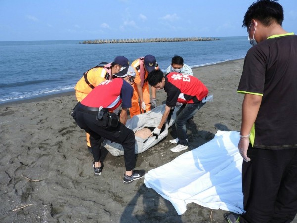 高雄茄萣海邊上午發現1具男浮屍，海巡和消防人員合力將遺體打撈上岸。（記者蘇福男翻攝）