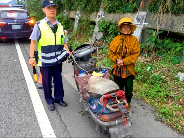 老婦騎機車從花蓮到台北尋女，誤闖台62線快速道路，基隆市警員賴文瑞（左）協助她回警所。（記者吳政峰翻攝）