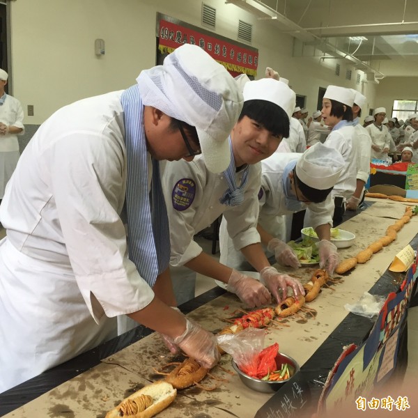 經國管理暨健康學院14日歡度49週年校慶；餐旅系與廚藝系共同舉辦廟口香腸堡競賽，學生將香腸堡接龍49公尺，祝賀經國學院49歲生日快樂。（記者俞肇福攝）