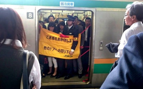 日本電車在昨天上班尖峰時間發生車門故障，使用了名為「安全簾」的塑膠布條阻擋後，在站務員陪同下繼續行駛。（圖擷自日本「朝日新聞」）