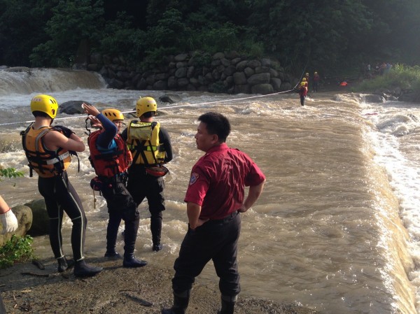 新竹縣北埔冷泉山區因下大雨溪水上漲，10名遊客受困對岸，消防隊員以拋繩槍搭繩跨越溪床搶救。（圖由新竹縣消防局提供）