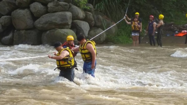 新竹縣北埔冷泉山區因下大雨溪水上漲，10名遊客受困對岸，消防隊員以拋繩槍搭繩跨越溪床搶救。（圖由新竹縣消防局提供）