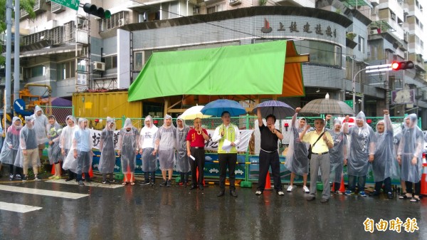 地主冒雨在馬路上拉白布條抗議，要求政府盡速處理土地補償費。（記者劉濱銓攝）