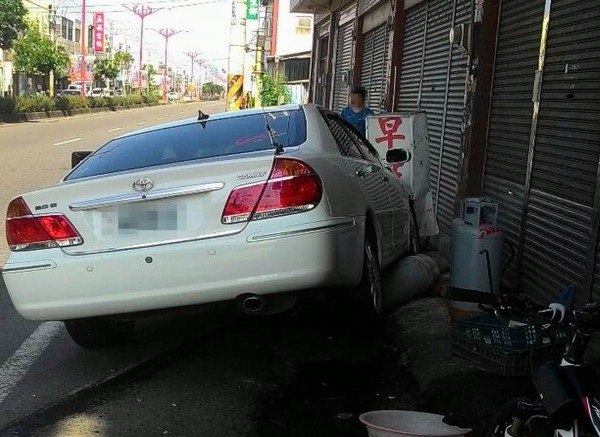 轎車衝早餐店後把店前的瓦斯桶撞倒壓在車底，現場民眾嚇得四散奔逃。（店家提供）