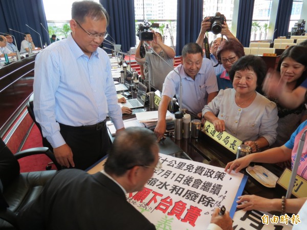 交通局長王義川（左立者）承諾公車10公里免費將繼續，否則下台負責，副市長林陵三也被議員要求簽名見證。（記者張菁雅攝）