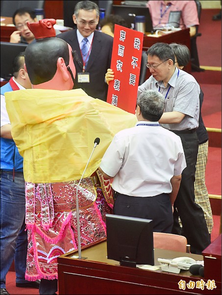 台北市議員陳重文質詢時，請來三太子穿雨衣向市長柯文哲（右）陳情，希望世大運不要穿雨衣表演。（記者簡榮豐攝）