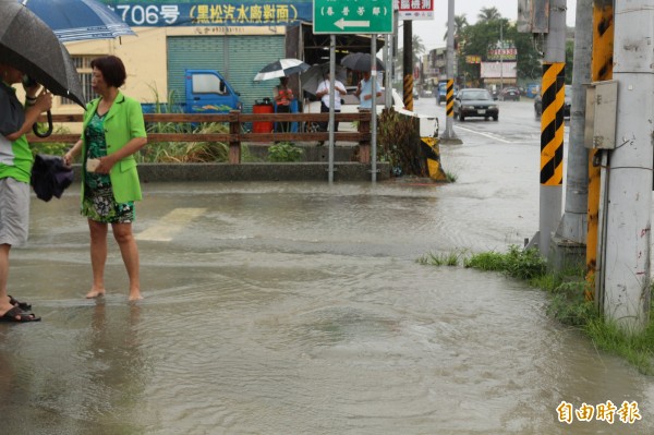 水從暗溝中湧出路面，造成淹水。（記者詹士弘攝）