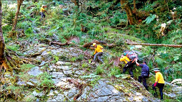 六龜分局森濤所長陳世光和員警與搜救人員輪流將林男遺體背下山。（記者黃佳琳翻攝）