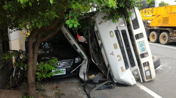 預拌混凝車過彎翻覆，壓扁路邊車輛。（記者詹士弘翻攝）