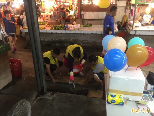 南市東區崇義市場工作人員把乳液倒進水流動的水溝，防止孳生病媒蚊幼蟲。（記者王俊忠攝）