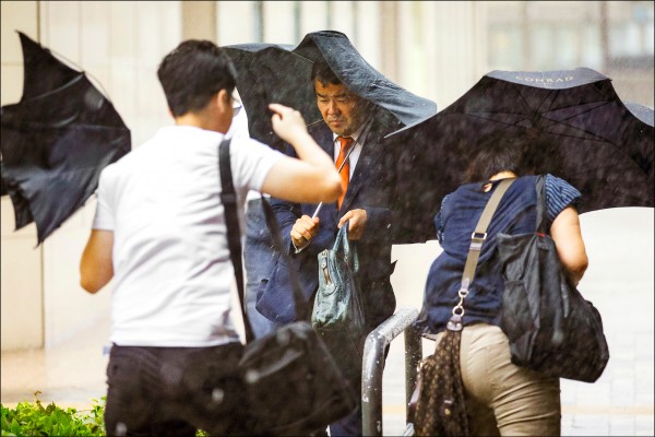 九號颱風「蒲公英」二十二日直撲日本東京首都地區，日本上班族仍冒雨出門上班。（歐新社）